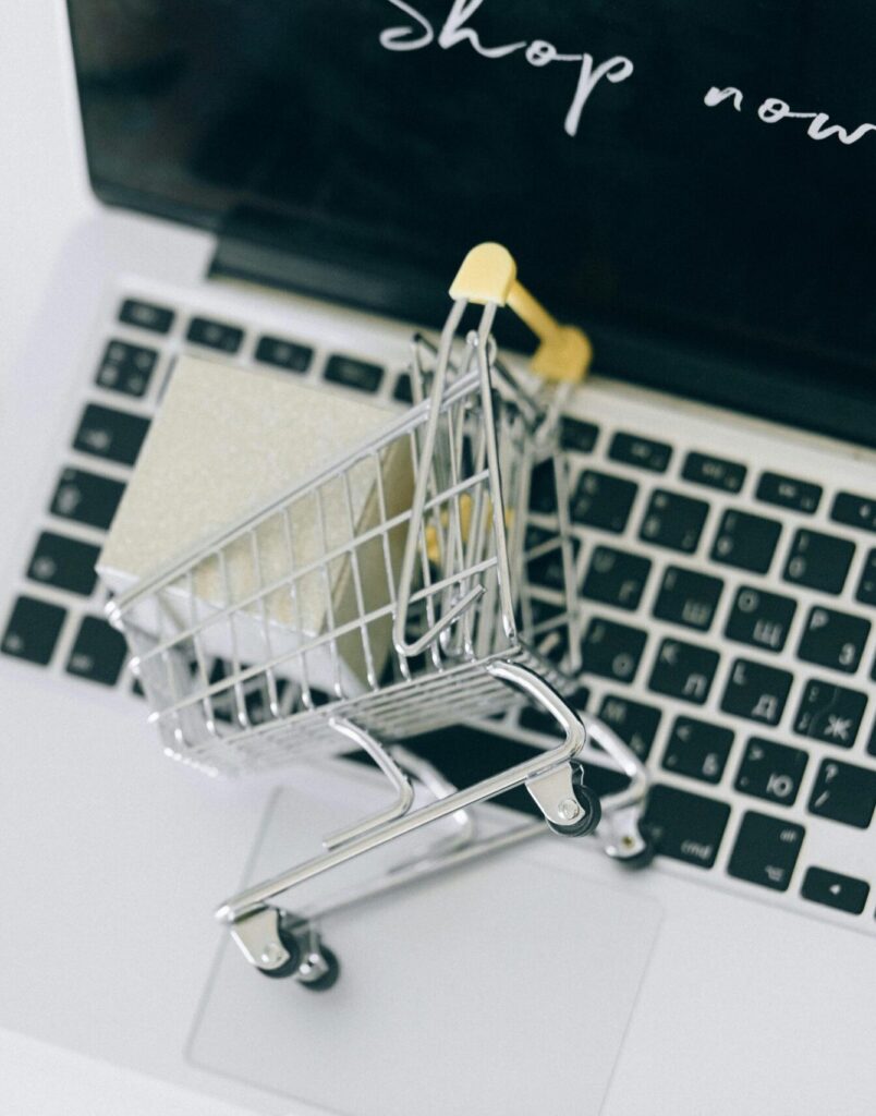 Creative depiction of online shopping with a miniature cart on a laptop keyboard.